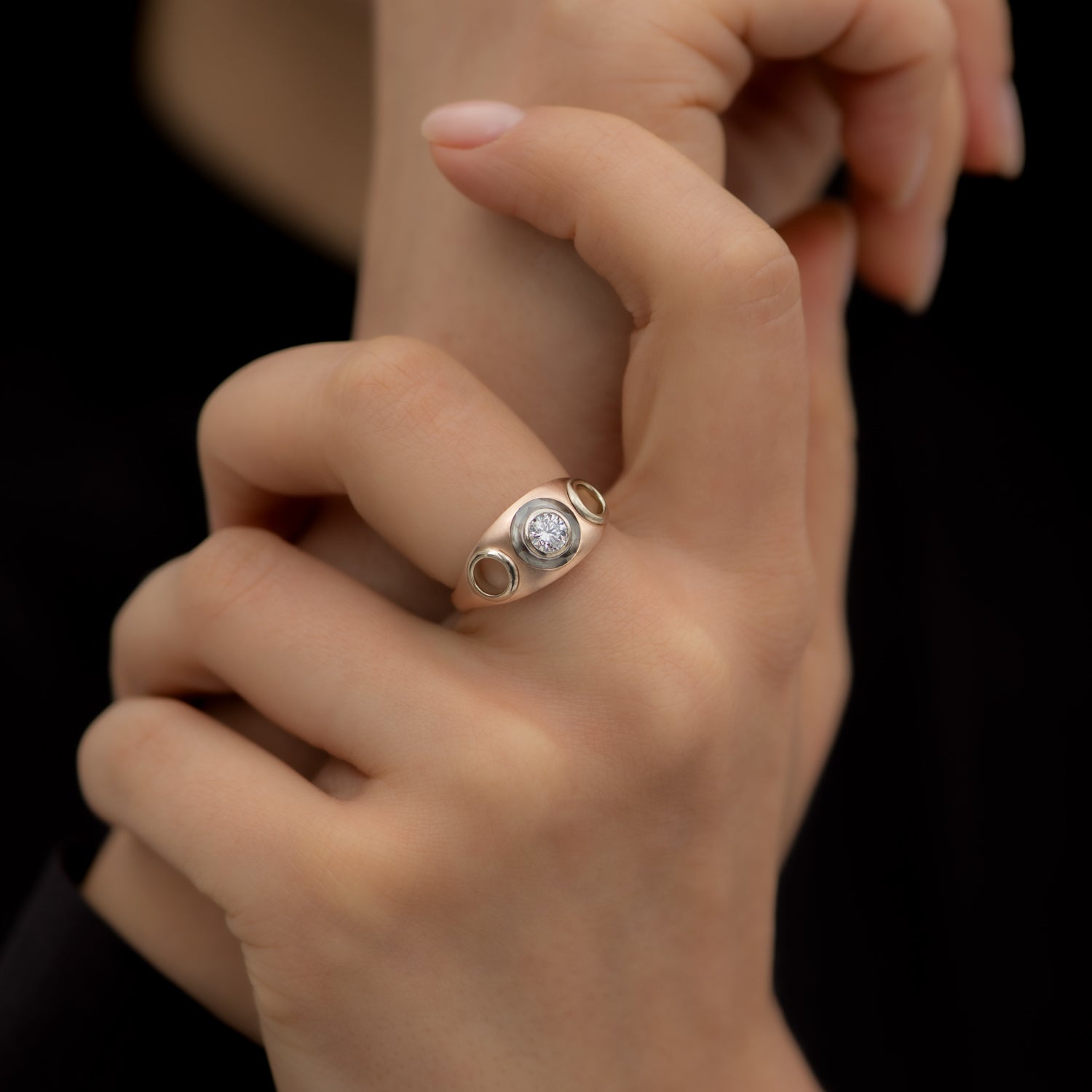 Piercing-Engagement-Ring-with-Grommets-and-a-Grey-Diamond-Halo-closeup-on-finger