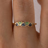 Gold ring with green and blue gemstones on a person's finger closeup