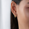 Gold earring worn by a person with a neutral background
