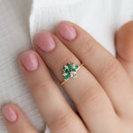 Emerald-and-Diamond-Cluster-Engagement-Ring-on-finger