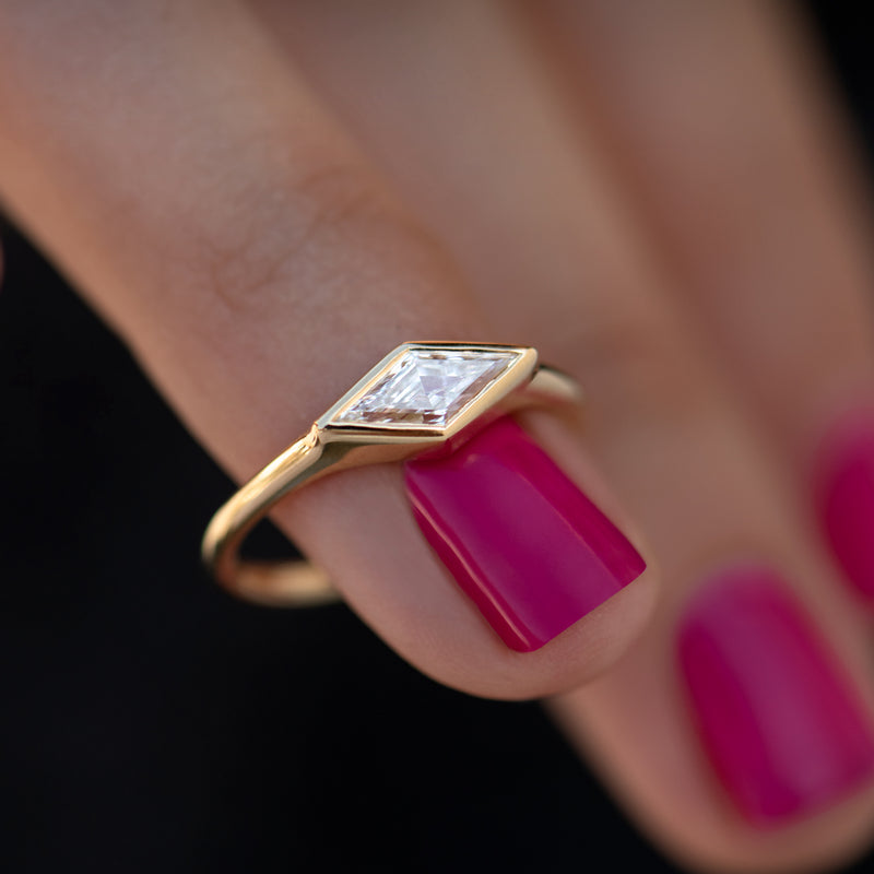 Lozenge-Cut-Diamond-Engagement-Ring-with-a-Golden-Bezel-on-finger