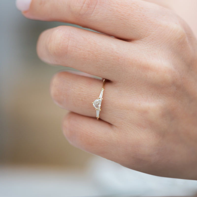 Three-Stone-Engagement-Ring-with-Half-Moon-and-Baguette-Cut-Diamonds-closeup-on-finger