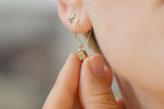 Tiny Cube Gold Earrings Between Fingers